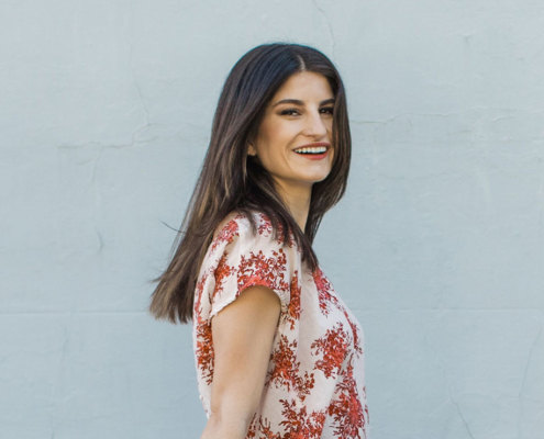 woman wearing a red floral blouse standing in front of a blue wall